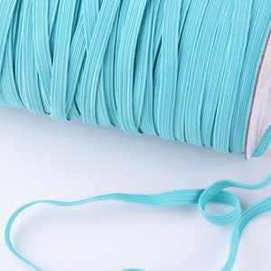 Peut inclure: Une bobine de cordon élastique turquoise. Le cordon est enroulé serré autour de la bobine et est prêt à être utilisé pour la couture ou les projets d'artisanat.
