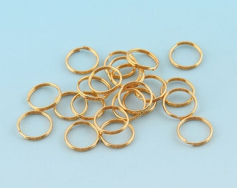 Könnte beinhalten: Ein Haufen goldfarbener Schlüsselringe aus Metall. Die Schlüsselringe sind alle gleich groß und gleich geformt und in einem zufälligen Muster angeordnet.