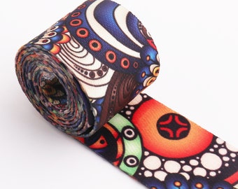 Könnte beinhalten: Ein farbenfrohes gemustertes Band mit einem blauen, orangen, weißen und schwarzen Design. Das Band ist aufgerollt und das Muster ist auf beiden Seiten sichtbar.