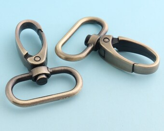 May include: Two antique gold-toned metal swivel clasps. The clasps are oval-shaped with a hook on one end and a loop on the other.