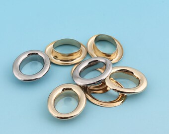 May include: A group of eight metal eyelets in two finishes: gold and silver. The eyelets are oval shaped and have a raised lip around the edge.