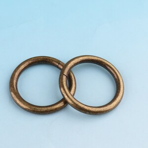 May include: Two antique gold-toned metal rings, interlocked, on a light blue background.