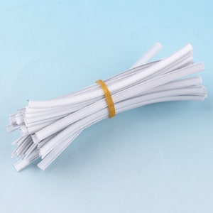 May include: A bundle of white plastic nose wire for face masks, secured with a yellow rubber band.