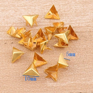 May include: A group of 17 gold-colored metal triangle pyramid studs, some are 5mm and some are 10mm in size.