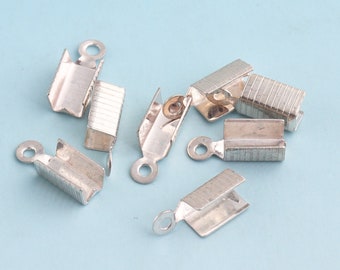 Op de afbeelding: Zilveren metalen sluitingen met een lus aan het ene uiteinde en een klein, rechthoekig, getextureerd stuk aan het andere uiteinde. De sluitingen zijn ontworpen om te worden gebruikt voor het maken van sieraden.
