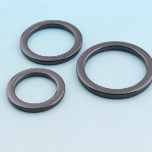 Puede incluir: Tres anillos de metal negro de diferentes tama&ntilde;os. Los anillos son lisos y tienen un acabado brillante.