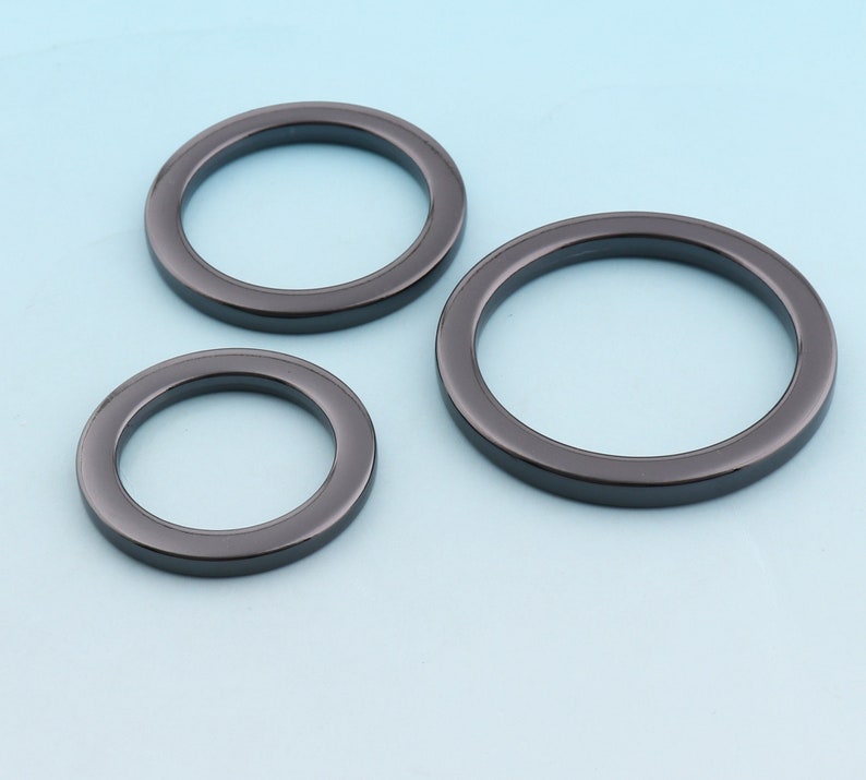 Puede incluir: Tres anillos de metal negro de diferentes tama&ntilde;os. Los anillos son lisos y tienen un acabado brillante.