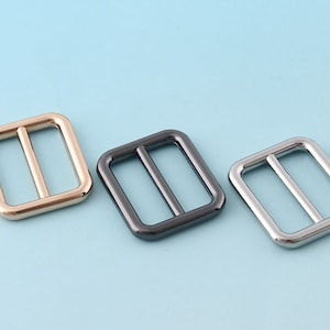 Puede incluir: Tres hebillas deslizantes de metal en dorado, negro y plateado.