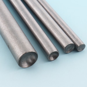 May include: Four metal rods of varying lengths and diameters, with rounded ends. The rods are arranged in a row, with the largest rod on the left and the smallest rod on the right.