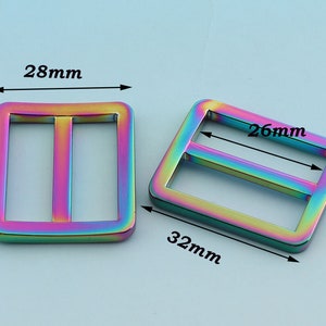 May include: Two iridescent metal slider buckles. The larger buckle measures 32 mm by 26 mm. The smaller buckle measures 28 mm by 28 mm.