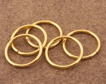 May include: Five gold-colored metal rings of different sizes, interlocked together.
