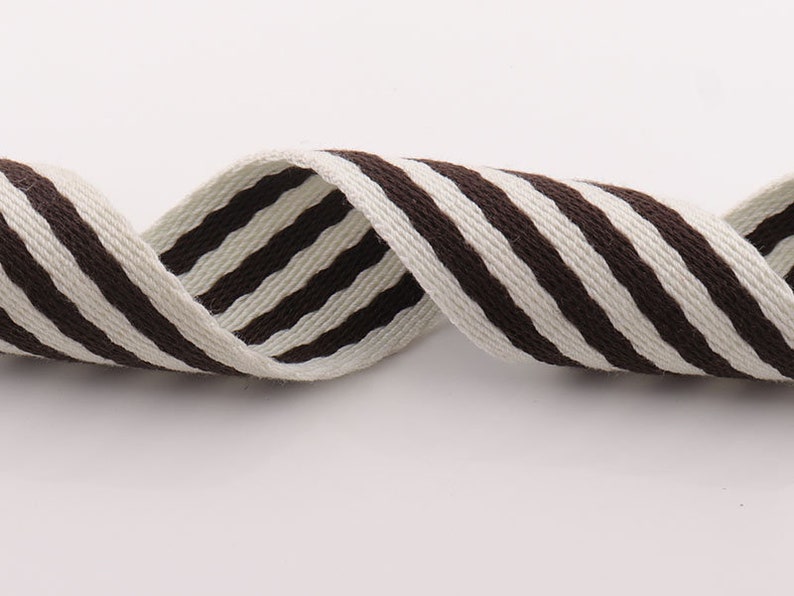 May include: Brown and white striped cotton webbing ribbon. The ribbon is woven with thick stripes and has a slightly textured surface.