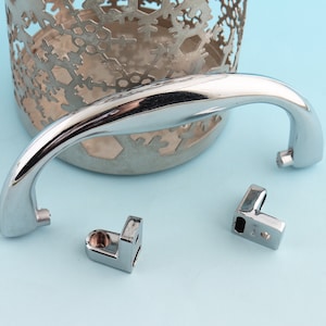 May include: A silver metal handle with a curved design. The handle is attached to a silver metal container with a snowflake pattern. Two silver metal corner brackets are also included.