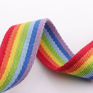 May include: Rainbow striped webbing with a woven texture. The webbing is red, orange, yellow, green, blue, purple, and red.