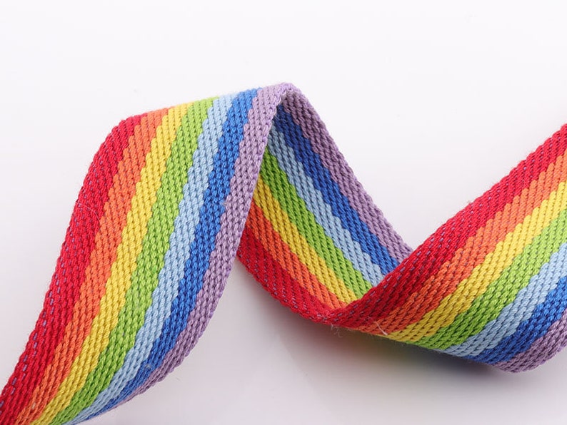 May include: Rainbow striped webbing with a woven texture. The webbing is red, orange, yellow, green, blue, purple, and red.
