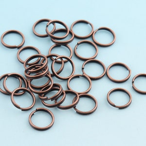 Könnte beinhalten: Ein Haufen kupferfarbener Metall-Sprünge. Die Ringe sind alle gleich groß und in einem zufälligen Muster angeordnet.