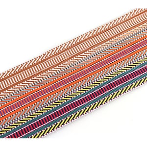 May include: Multicolored woven ribbon with a geometric pattern. The ribbon features a variety of colors, including orange, red, green, yellow, and blue.