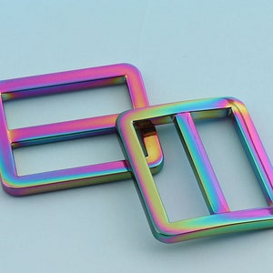 May include: Two iridescent metal slider buckles. The buckles are rectangular with rounded corners and have a smooth, shiny finish.
