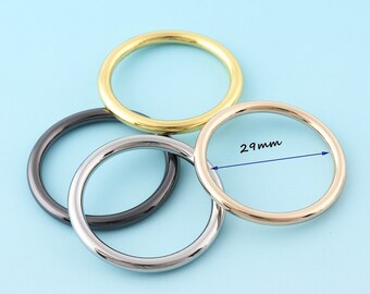 May include: Three metal rings, one gold, one silver, and one black, with the gold ring measuring 29 mm in diameter.