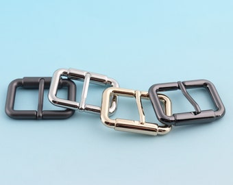 May include: Four metal belt buckle closures in different finishes: silver, black, and gold. The buckles are square shaped with rounded corners and have a smooth finish.