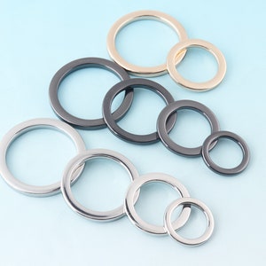May include: Assortment of metal rings in different sizes and finishes, including gold, silver, and black.