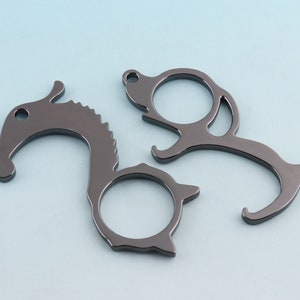 May include: Two black metal door openers. One is shaped like a horse head and the other is shaped like a stylized bird. Both have a loop for attaching to a keychain.