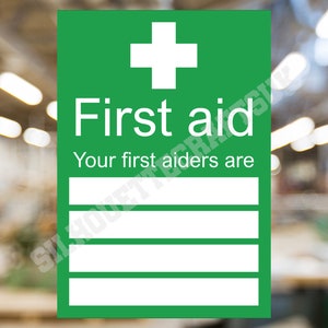 May include: Green first aid sign with a white cross and the text "First aid" and "Your first aiders are". There are four blank lines below the text for names.