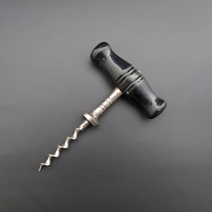May include: A vintage corkscrew with a black wooden handle and a silver metal spiral.