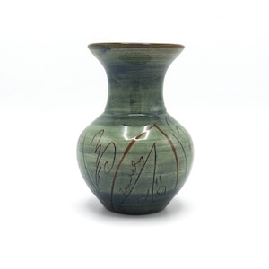 May include: A small, green ceramic vase with a brown glaze and a design of stylised leaves. The vase has a narrow neck and a rounded body.