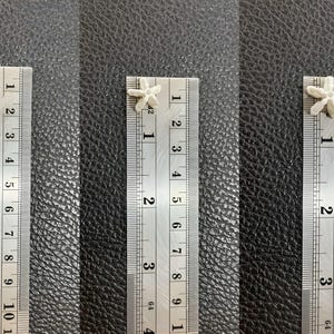 Measurement scale showing the exact size in millimeters for small, medium, and large white crown flower beads for precision craft projects.