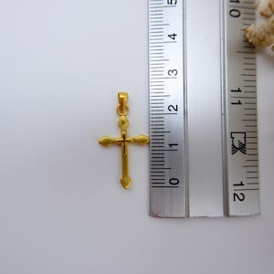 Close-up of a 999 pure gold cross pendant placed next to a silver measuring ruler, showing the pendant’s small and delicate size for accuracy. Ideal for customers seeking a lightweight gold Christian pendant for necklace chains. The minimalist hollow design makes it perfect for daily wear, baptism, or religious gifts. Includes dried white baby’s breath in the corner to enhance elegance. Great for Etsy searches related to gold religious jewelry and small gold cross charms.