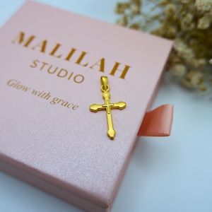 Elegant display of a 999 pure gold cross pendant resting on a soft pink jewelry box with "MALILAH STUDIO" and "Glow with grace" embossed in gold foil. This dainty, lightweight hollow cross charm is perfect as a religious gift, baptism necklace, or everyday Christian jewelry piece. Floral elements of dried white baby’s breath add a soft, feminine touch. Ideal for Etsy searches like gold cross pendant, real gold Christian charm, or minimalist gold faith jewelry.