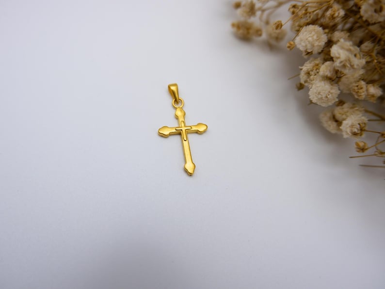 Close-up image of a 999 pure gold cross pendant with a minimalist and elegant design, photographed on a soft white background next to dried white baby’s breath flowers. This high-quality real gold religious necklace charm features a lightweight, hollow design and is ideal for men or women who want a meaningful Christian gift or a faith-based jewelry piece. Perfect for Easter, baptism, confirmation, or everyday spiritual wear. Suitable for Etsy SEO targeting faith jewelry.