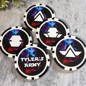 May include: A collection of five round poker chips. Each chip features a black and white border with a unique white geometric design on a colorful galaxy background. One chip displays the text "TYLER'S ARMY".
