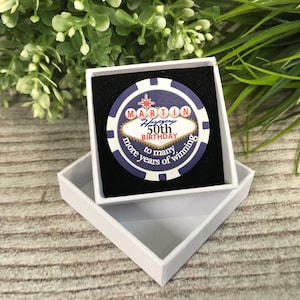 May include: A blue and white casino chip with a gold star and the text "MARTIN Happy 50th Birthday to many more years of winning" in a white box.