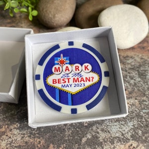 May include: A blue and white poker chip with a Vegas-themed design. The chip says "Mark Be My Best Man? May 2023".