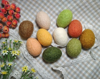 May include: Ten felt Easter eggs in various colors, including green, brown, orange, yellow, and white, arranged on a checkered fabric background.