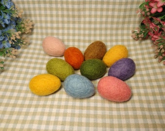 May include: Nine felt Easter eggs in various colors, including pink, orange, green, brown, purple, blue, and yellow. The eggs are arranged in a circle on a checkered tablecloth.