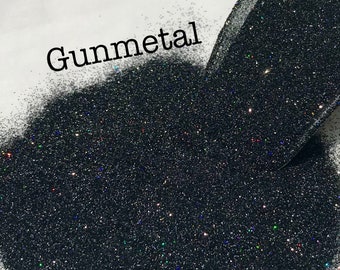 May include: A close-up of a pile of black glitter with iridescent sparkles. The glitter is labeled "Gunmetal".