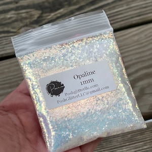 May include: A small resealable bag filled with iridescent opal glitter. The bag has a label that reads "Opaline 1mm" and includes the website and email address for PoshGlitterLLC.com.