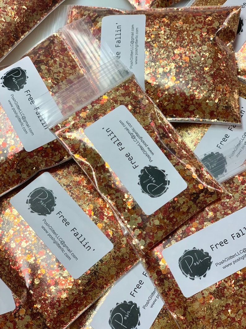 K&ouml;nnte beinhalten: Klare Plastikt&uuml;ten gef&uuml;llt mit einer Mischung aus goldenem, kupferfarbenem und rotem Glitzer. Jede T&uuml;te hat ein wei&szlig;es Etikett mit dem Text "Free Fallin'" und dem PoshGlitter-Logo. Der Glitzer ist eine Mischung aus Formen und Gr&ouml;&szlig;en.