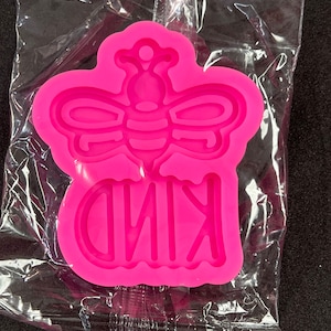 May include: Pink silicone mold for resin crafts featuring a bee with wings and the word "KIND" underneath.