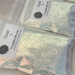 May include: A clear plastic bag filled with iridescent white glitter. The bag has a label that says "Cloud 9" and "Poshglitterllc.com".
