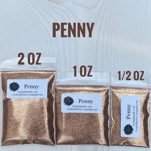 May include: Three bags of copper glitter labeled "Penny" with sizes 2 oz, 1 oz, and 1/2 oz. The bags are on a light wood background.