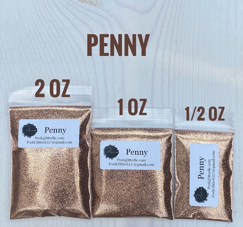 May include: Three bags of copper glitter labeled "Penny" with sizes 2 oz, 1 oz, and 1/2 oz. The bags are on a light wood background.