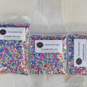 May include: Three clear plastic bags filled with colorful glitter. Each bag has a white label with the text "Kaleidoscope" and the seller's logo and contact information. The glitter appears to be a mix of various shapes and colors, including pink, blue, green, and yellow.