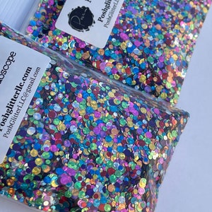 May include: Two clear plastic bags filled with colorful, iridescent glitter. The glitter is a mix of round shapes in various colors, including blue, purple, green, and gold. Each bag has a white label with the text "Kaleidoscope" and "PoshGlitterLLC.com".