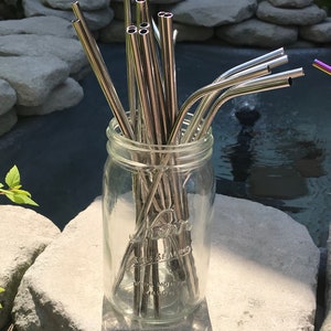 May include: A glass jar filled with a bundle of silver metal reusable drinking straws. The jar is labeled "Self Sealing Wide Mouth Mason".