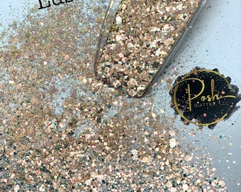 May include: A close-up of a clear scoop filled with glitter. The glitter is a mix of gold, rose gold, and teal colors. The word "Lush" is written in black font. The logo for Posh Glitter LLC is in the bottom right corner.