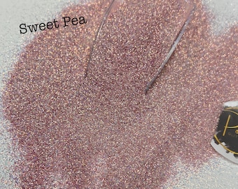 May include: A close-up of a pile of fine pink glitter with iridescent shimmer. The glitter is labeled "Sweet Pea".